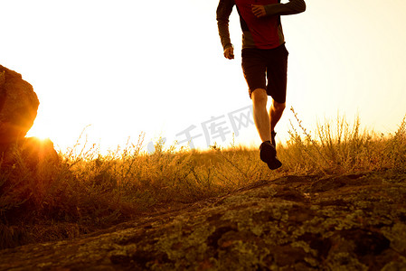 奔跑的运动员摄影照片_日落时在落基山小径上奔跑的运动员腿部特写。