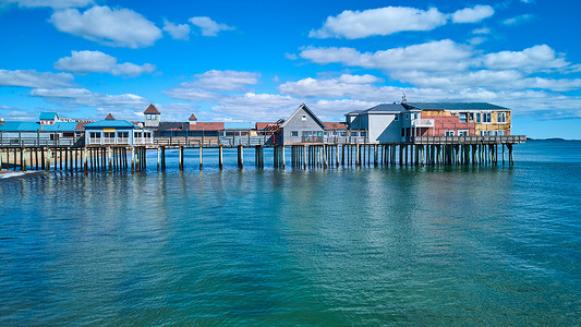 缅因州商店覆盖着海洋和蓝天的长旧木码头的空中侧面轮廓