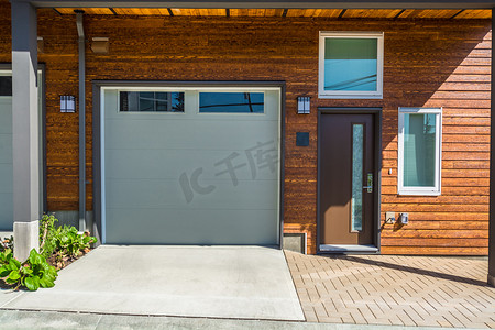 全新联排别墅的入口和车库门，带木质壁板墙板。
