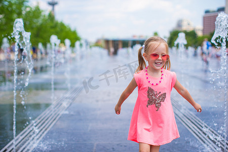 小可爱女孩在街头喷泉玩得开心