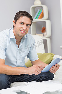 在客厅里用数字平板电脑拿着账单的微笑男人