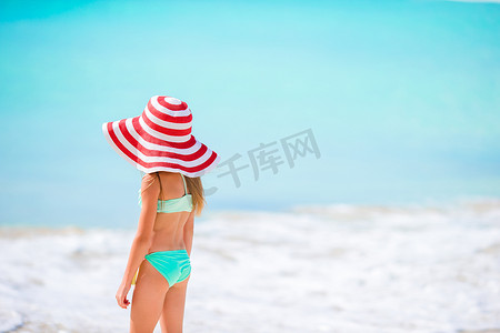 大红色帽子的可爱的小女孩在热带海滩