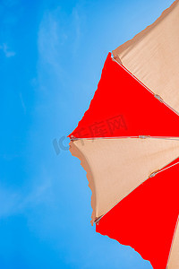 一把红色和黄色太阳伞的特写镜头在蓝天背景的