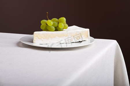 萌萌的卡通脸摄影照片_亚麻桌布上的卡门培尔奶酪和葡萄