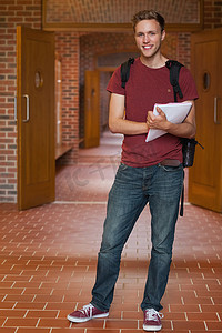 站立在走廊的英俊的快乐的学生