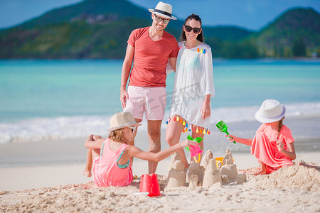 家庭在暑假的白色沙滩上制作沙堡