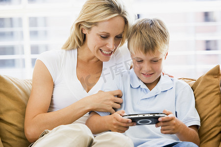 玩电脑的人摄影照片_客厅里的女人和小男孩带着手持视频游戏微笑