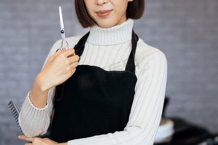 手持合格理发工具的年轻亚洲女美发师的画像。
