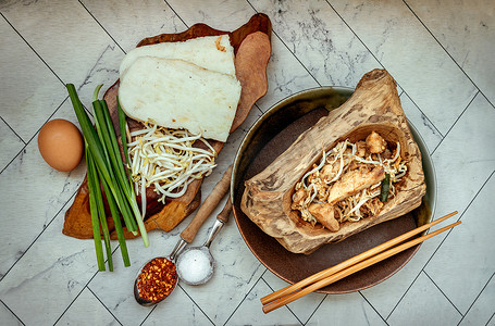 在陶瓷盘中用豆芽和细香葱炒软萝卜糕或炒萝卜糕 (chai tow kway)。