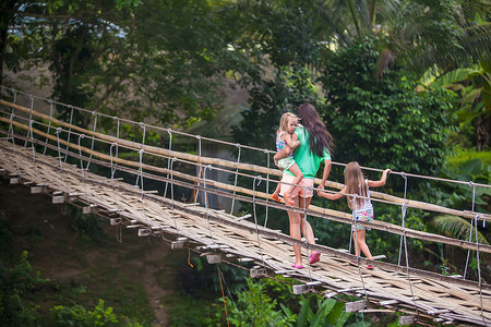 在菲律宾洛博克河上的吊桥上行走的小女孩和年轻妇女
