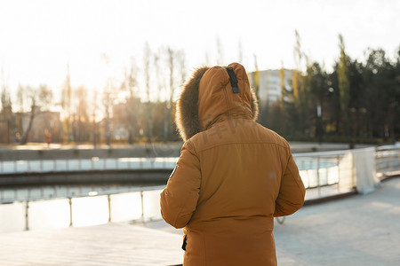 冬季公园穿着保暖衣服和头巾行走的人的后视-寒冷季节概念