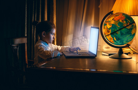 小女孩晚上在笔记本电脑上做作业