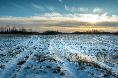 与农田和云彩后的落日的冬天风景