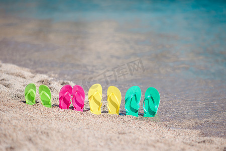 人字拖印花摄影照片_海边沙滩上的家庭彩色人字拖