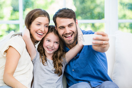 家长手机摄影照片_笑着的家人用智能手机点击自拍