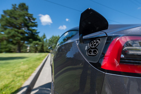 夏季户外黑色电动汽车充电插座的特写。