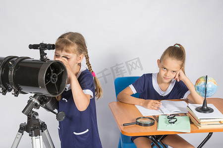 女天文学家通过望远镜看天空，另一个女孩坐在桌旁