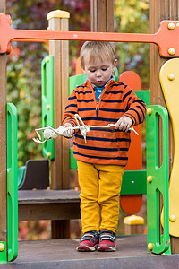 万圣节时，一个穿条纹毛衣的小孩手里拿着骷髅玩具