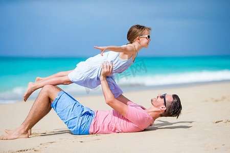 父亲一家和运动型小女孩在沙滩上玩得开心