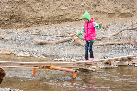 过河摄影照片_七岁的女孩在临时搭建的桥上被轻轻地移过小溪