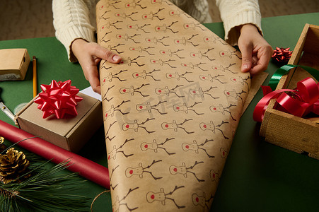 特写女人推出带有鹿图案的包装礼品纸，包装圣诞礼物。