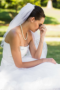 婚纱项链摄影照片_坐在公园的美丽的担心的新娘