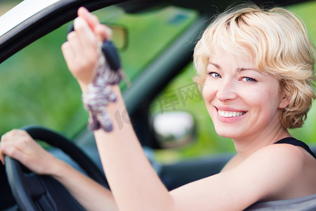 女士，正在开车，将车钥匙展示在窗外。