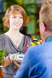 优惠券卡券摄影照片_使用电子优惠券的微笑的年轻花店顾客