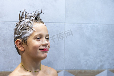 一个快乐的男孩在浴室里用洗发水洗头