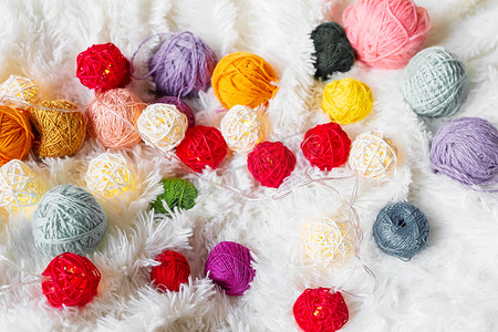 毛茸茸的毯子上铺着鲜艳的彩色针织纱和发光的球形花环。
