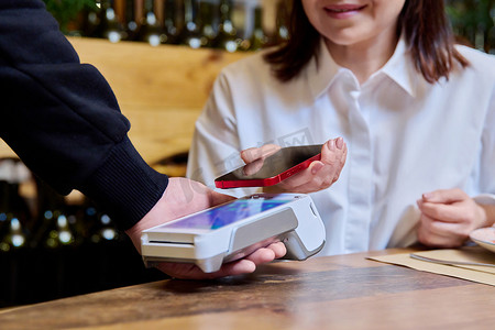 餐厅的女性使用智能手机和终端支付订单