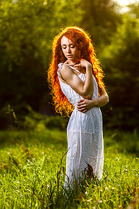走在日落森林光芒下的红头发人女孩