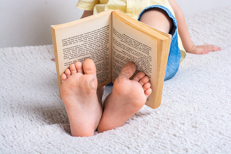 书店读书的人摄影照片_男孩脚上拿着书作为世界读书日的概念
