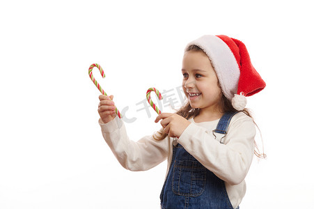 戴着圣诞帽的可爱女婴，用绿色红色糖果手杖指着复制广告空间，表达幸福和快乐