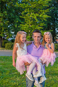 年轻的父亲和他可爱的女儿们在户外玩得开心