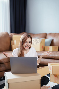 创办独立亚洲女性在线卖家的小企业企业家，通过电脑与客户视频交谈，并包装产品交付给客户。