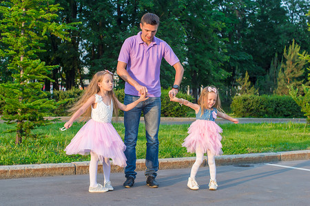 年轻的爸爸和他可爱的女儿们在户外玩得开心