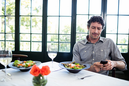 智能酒店摄影照片_餐馆里使用手机的男人
