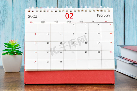 红色2023背景摄影照片_2023 年 2 月的 2023 年月度台历，书籍为蓝色木质背景。