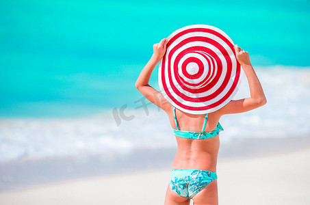 大帽子的可爱的小女孩在白色沙子加勒比海滩