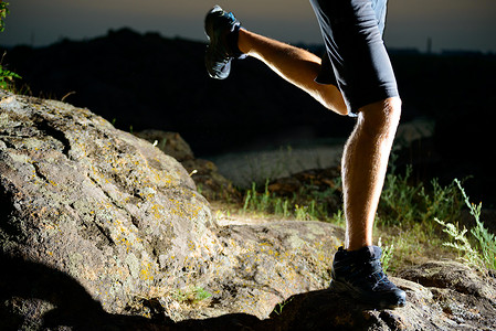 夜间在落基山小径上奔跑的运动员腿部特写。