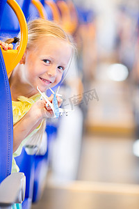 可爱的小女孩在火车上旅行，手里拿着飞机模型玩得开心
