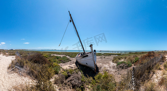 放射蓝色摄影照片_Ria Formosa 沼泽地沙丘植被上的弃船