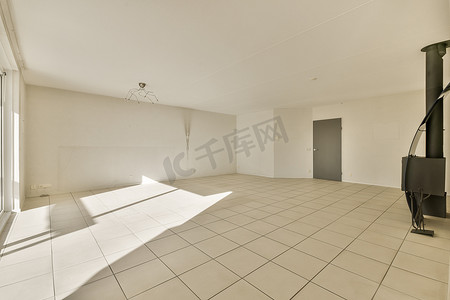 平铺摄影照片_一间空荡荡的客厅，铺着白色瓷砖地板