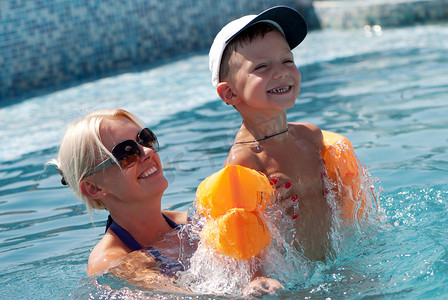 微笑的美女和小男孩在游泳池里洗澡