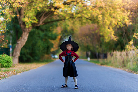 在万圣节派对上，穿着女巫服装的小女孩站在路上
