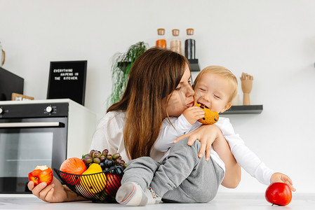 幸福的家庭妈妈抱着婴儿吃苹果和健康食品。