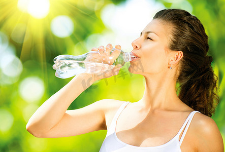 健康和运动的年轻女人从瓶子里喝水