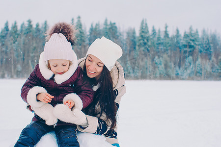 雪天摄影照片_幸福的妈妈和孩子家庭享受冬天的雪天