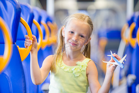 可爱的小女孩在火车上旅行，手里拿着飞机模型玩得开心